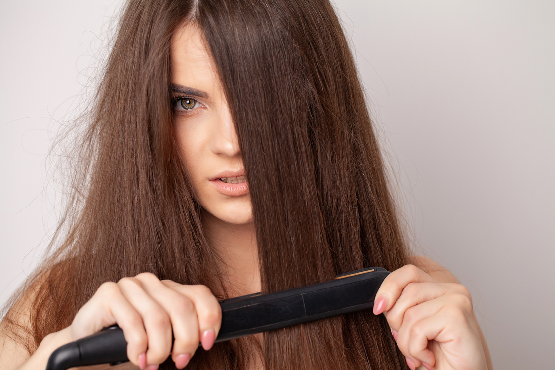 Woman with Beautiful Long Straight Hair Using a Hair Straightener